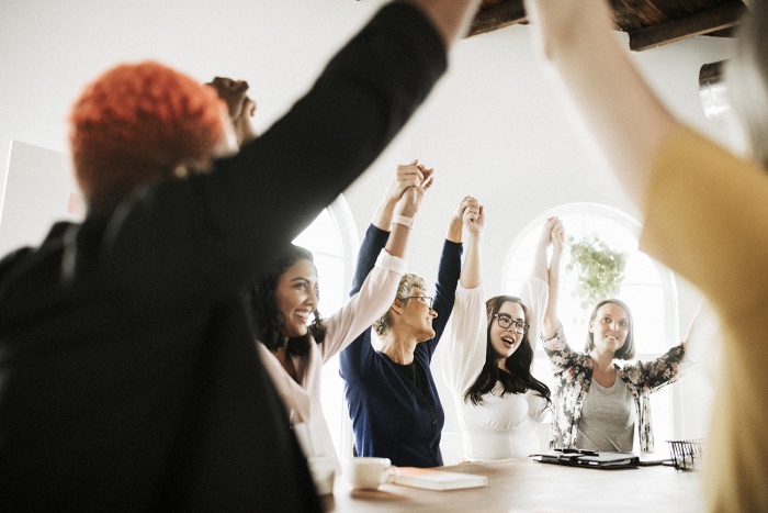 A group of business women celebrate around a table