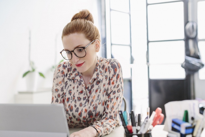 A young woman works in an office at a computer