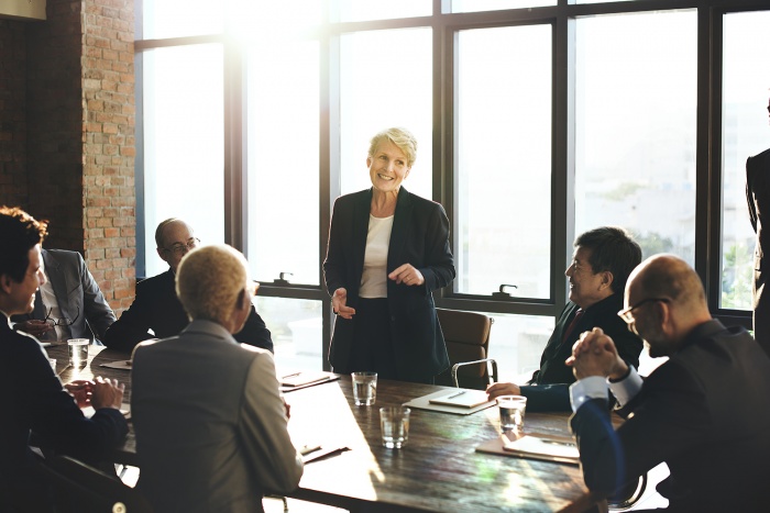 A business woman gives a presentation to a room full of colleagues