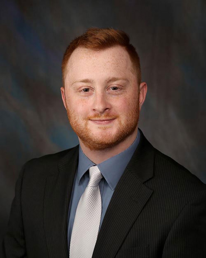 A man in a suit and tie with a slight smile