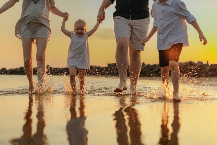Family running in water reflected by the sunset