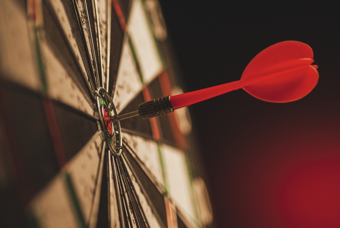 A dart sits squarely in the bullseye of a dart board.