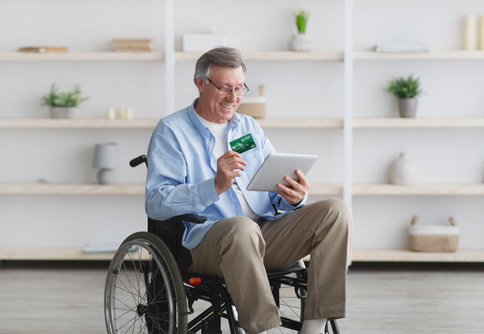 Happy senior man in wheelchair holding HFCU Visa