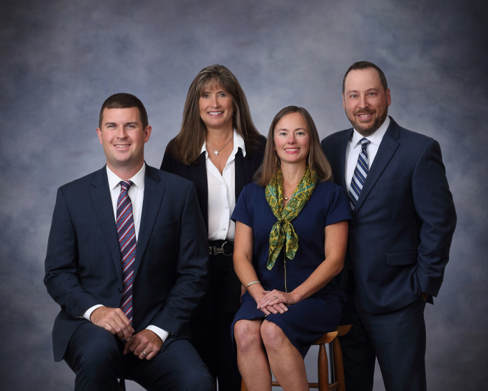 The four team members of the Heritage Way team, two males and two females, pose for a photo in business attire