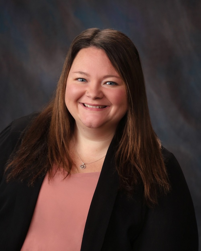 A smiling woman, Mackenzie Warner, in business attire