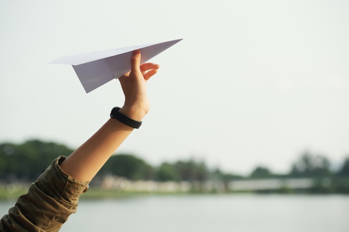 A woman is about to throw a paper airplane through the air.