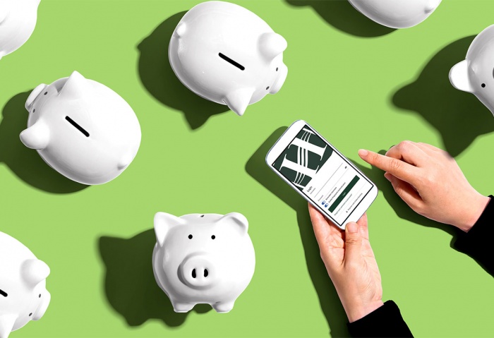 A person holds a mobile phone logging into eBranch surrounded by white piggy banks