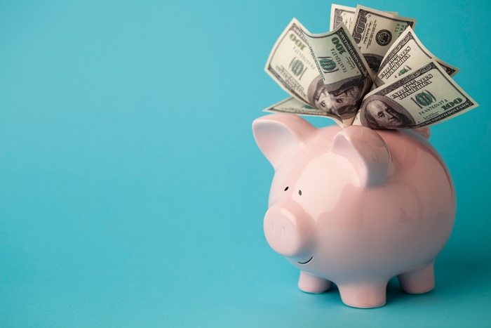 piggy bank filled with bills on blue background