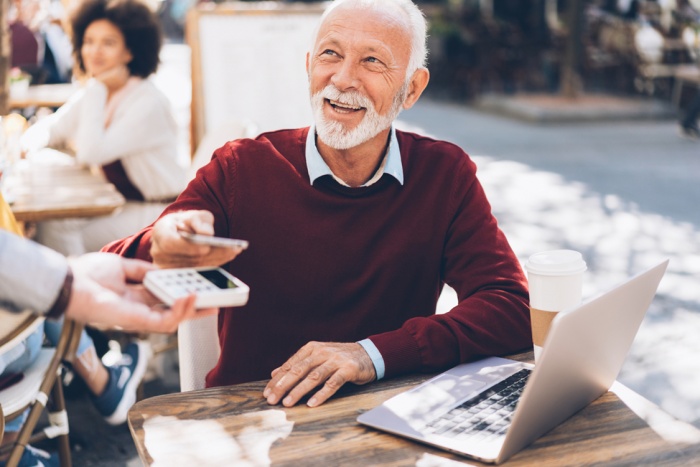 Senior businessman paying contactless at cafe