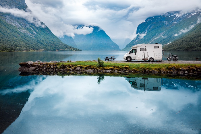 A RV and a motorcycle are parked next to a misty lake