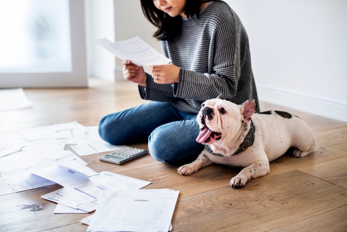 Woman sitting on floor with bulldog reviewing bills