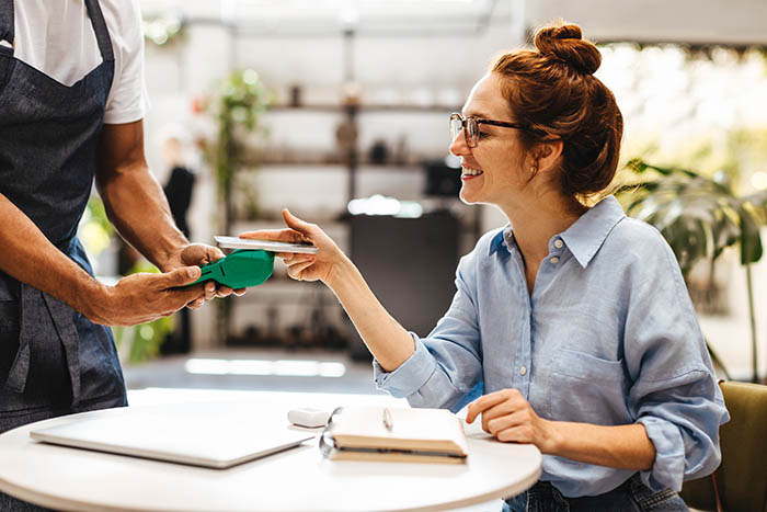 Woman using tap-to-pay on a smartphone at a restaurant