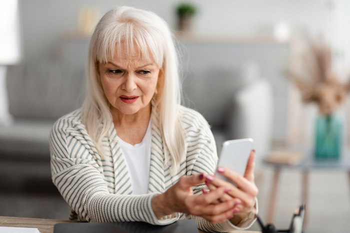 worried senior woman looks at phone