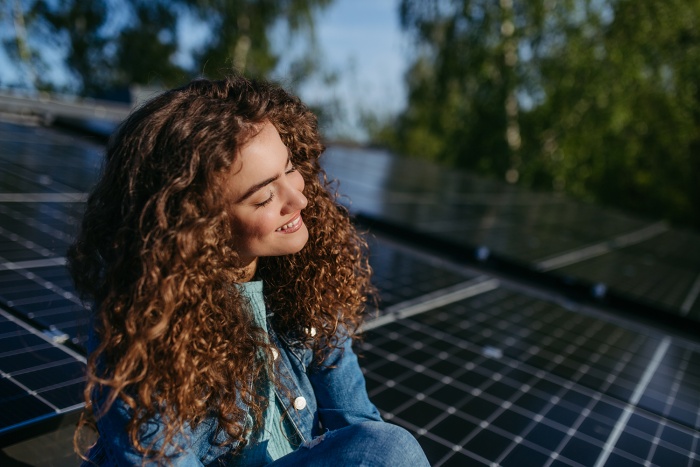 A young woman sits amongst solar panels