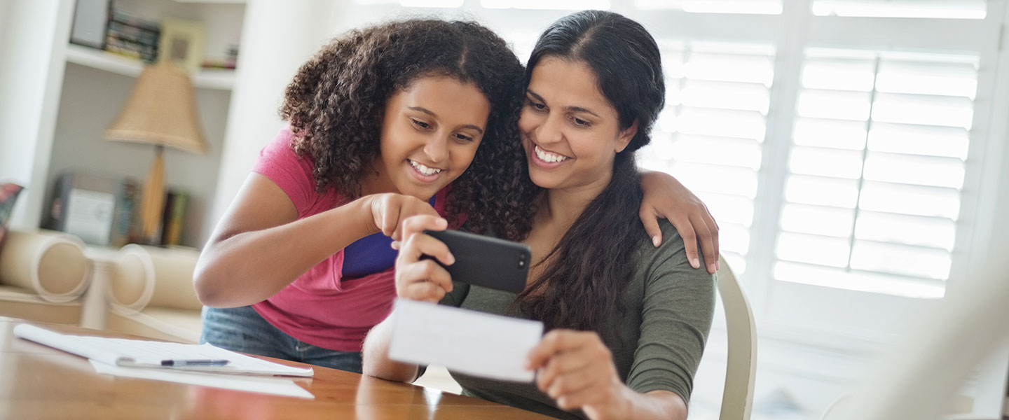 Mother and daughter using mobile deposit