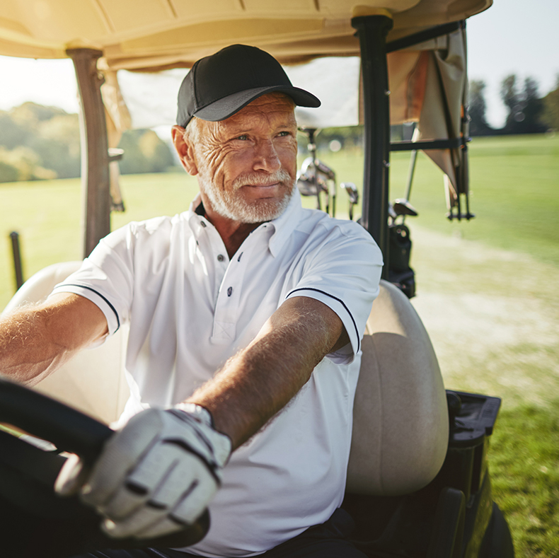 A retired man drives a golf cart