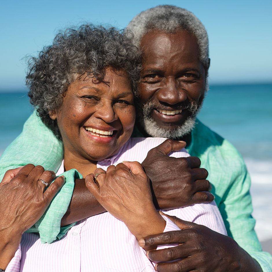 An older couple poses on the beach