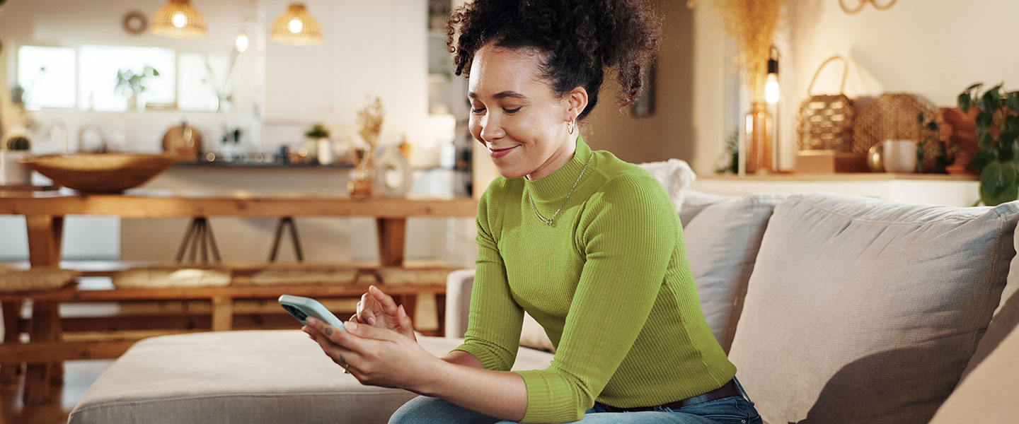 Woman on phone smiling on sofa